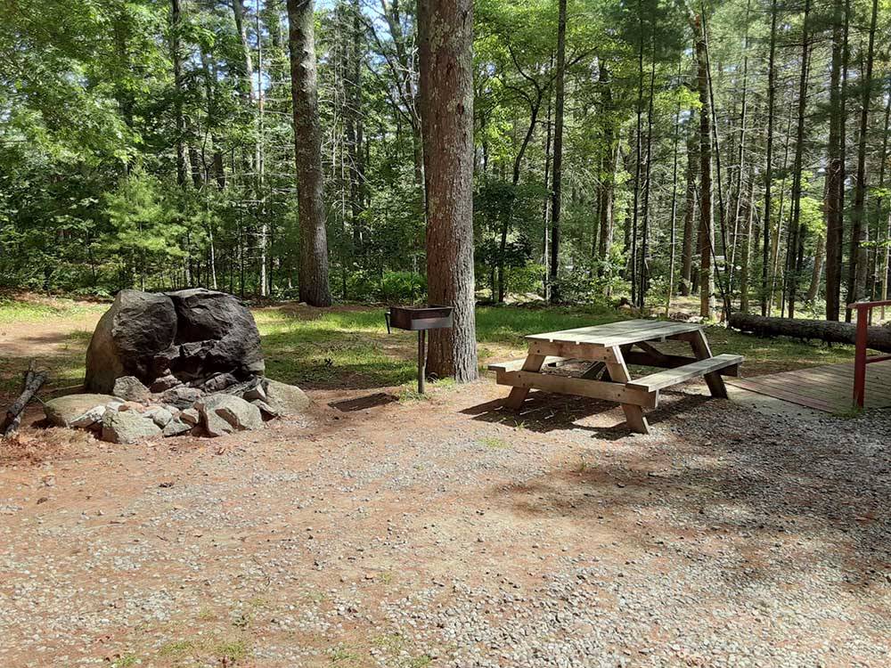 A bbq pit and bench next to a rock formation at NATURES CAMPSITES