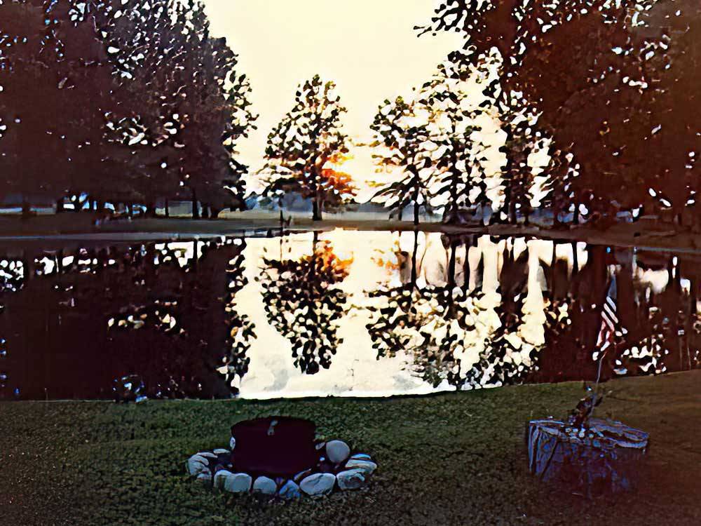 Fire pit near water, reflecting trees at CHEROKEE PARK CAMPGROUND
