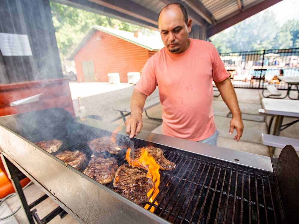 A man grilling food on the bbq pit at MUNDS PARK RV RESORT