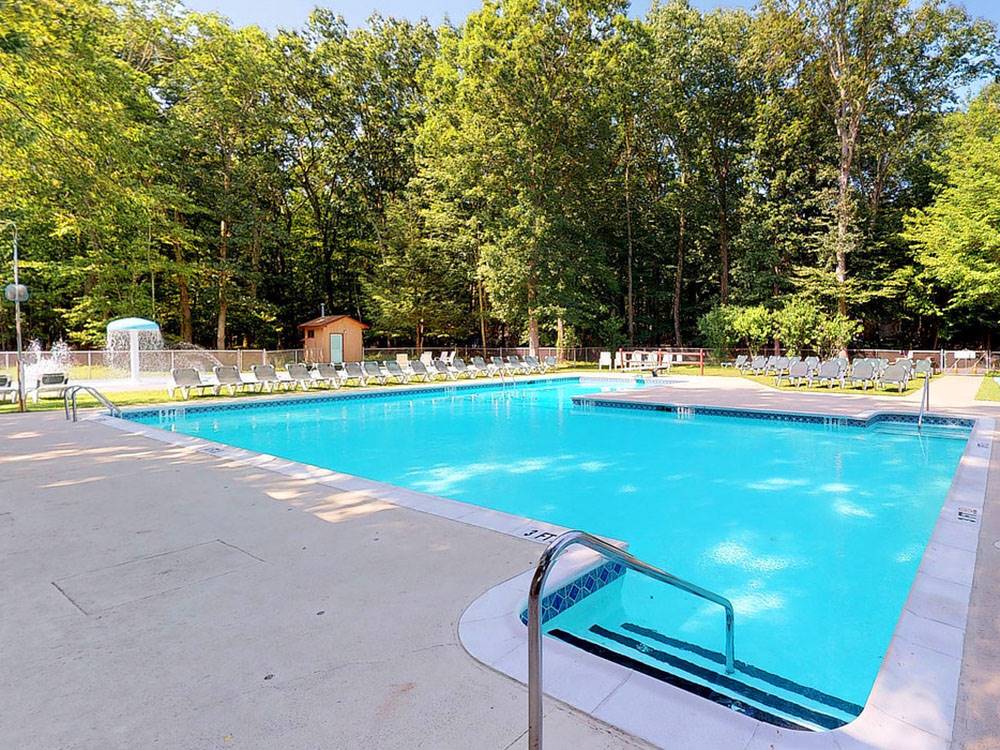 Swimming pool with white lounge chairs at OTTER LAKE CAMP RESORT