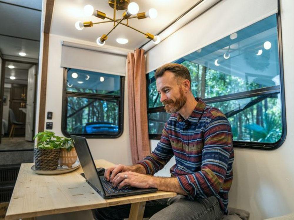 Man sitting at table on computer in RV at WHIP IN RV PARK