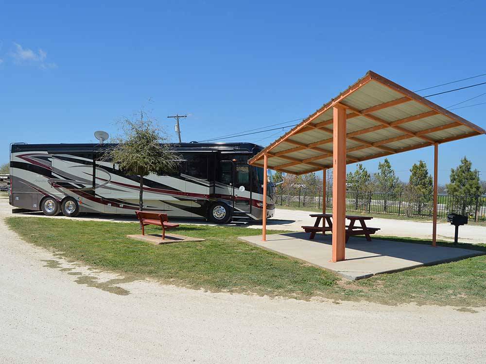 Site with RV and covered picnic table at ABILENE RV PARK
