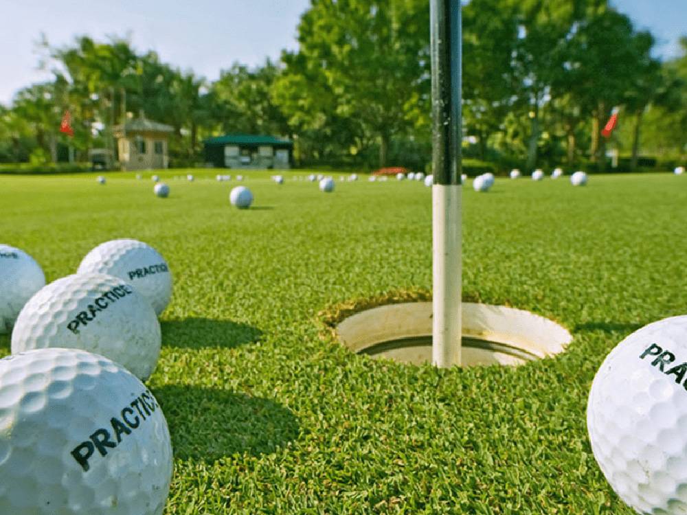 Golf balls on green near golf cup and flagstick