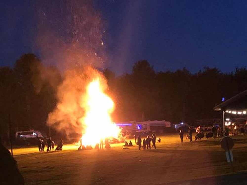 People surrounding a large bonfire at COUNTRY ROADS CAMPGROUND