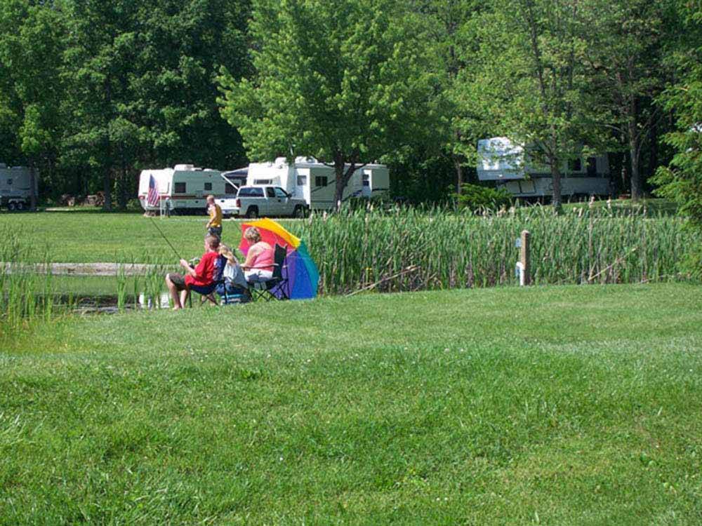 A couple sitting along the water fishing at SUN VALLEY CAMPGROUND