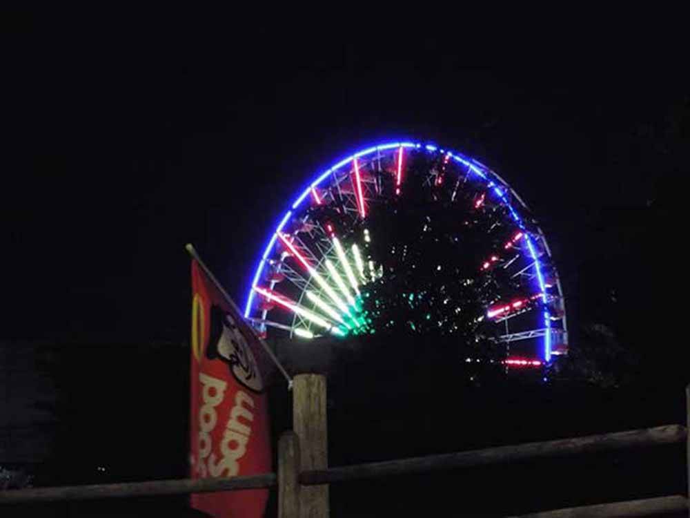 A lit up Ferris wheel at night at MUSICLAND KAMPGROUND