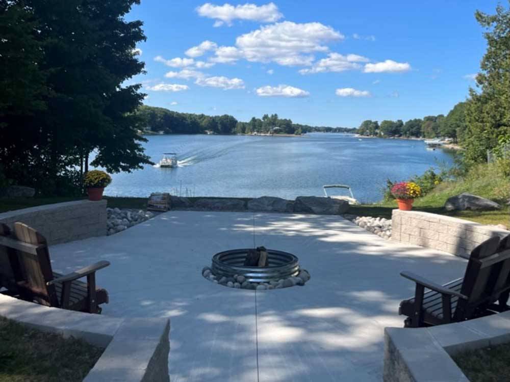 Fire pit area near the bank of a lake with boats at HOLIDAY PARK CAMPGROUND