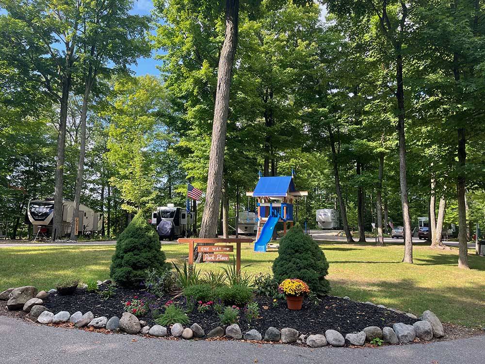 Flowers and trees in grassy area near play structure at HOLIDAY PARK CAMPGROUND