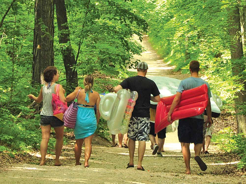 A family walking through the trail leading to waterpark at PLYMOUTH ROCK CAMPING RESORT