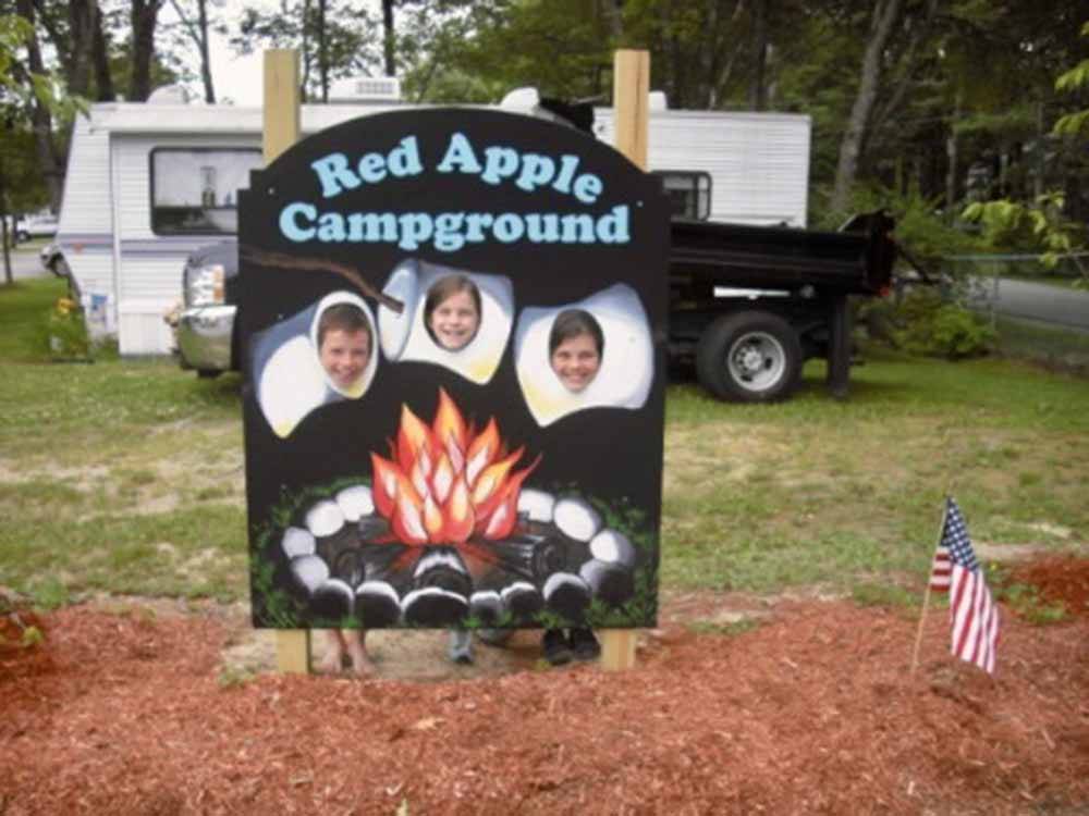Three kids sticking their heads thru a sign so they look like marshmallows roasting over a fire at RED APPLE CAMPGROUND