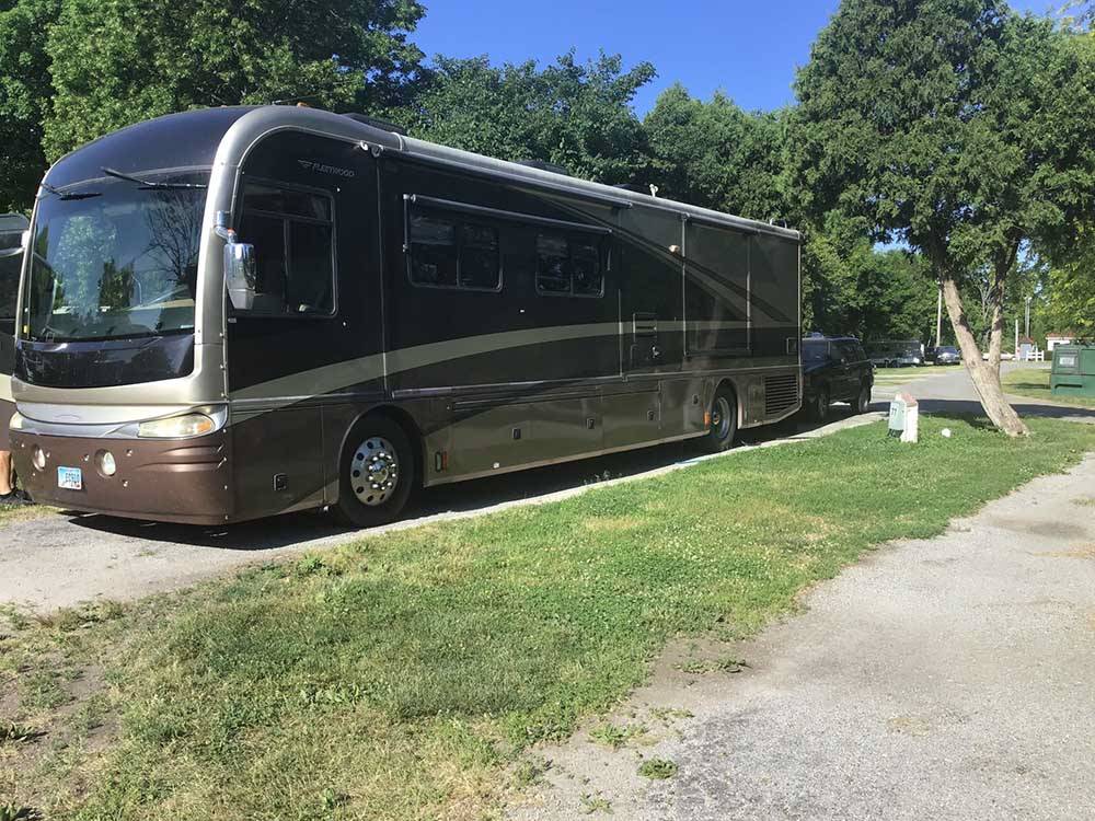A brown and tan motorhome parked in a gravel site at ENON BEACH CAMPGROUND