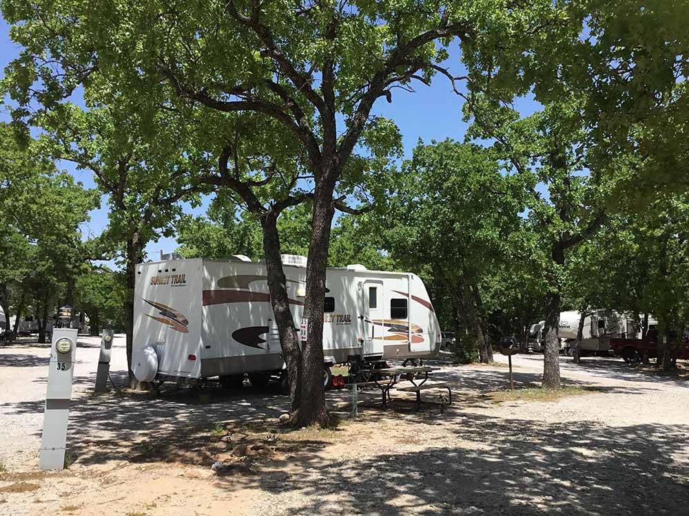 A travel trailer under a tree at CAMPER'S PARADISE RV PARK