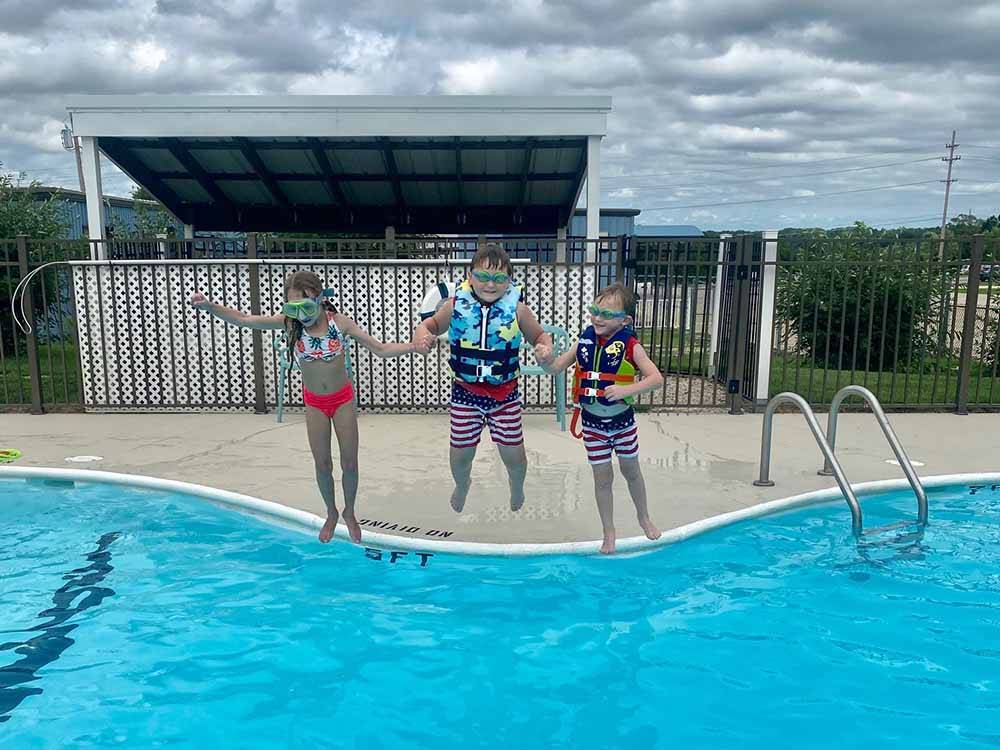 Kids jumping into the swimming pool at OSAGE BEACH RV PARK