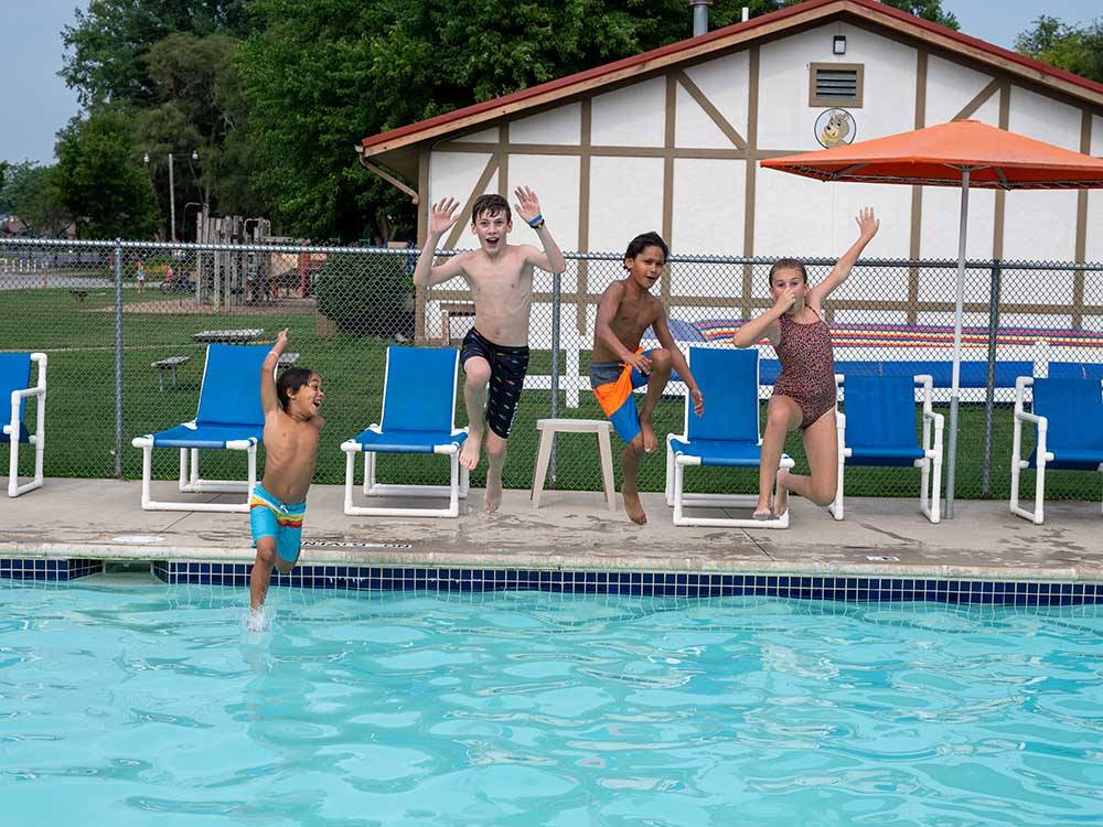 A group of kids jumping into the swimming pool at FRANKENMUTH YOGI BEAR'S JELLYSTONE PARK CAMP-RESORT