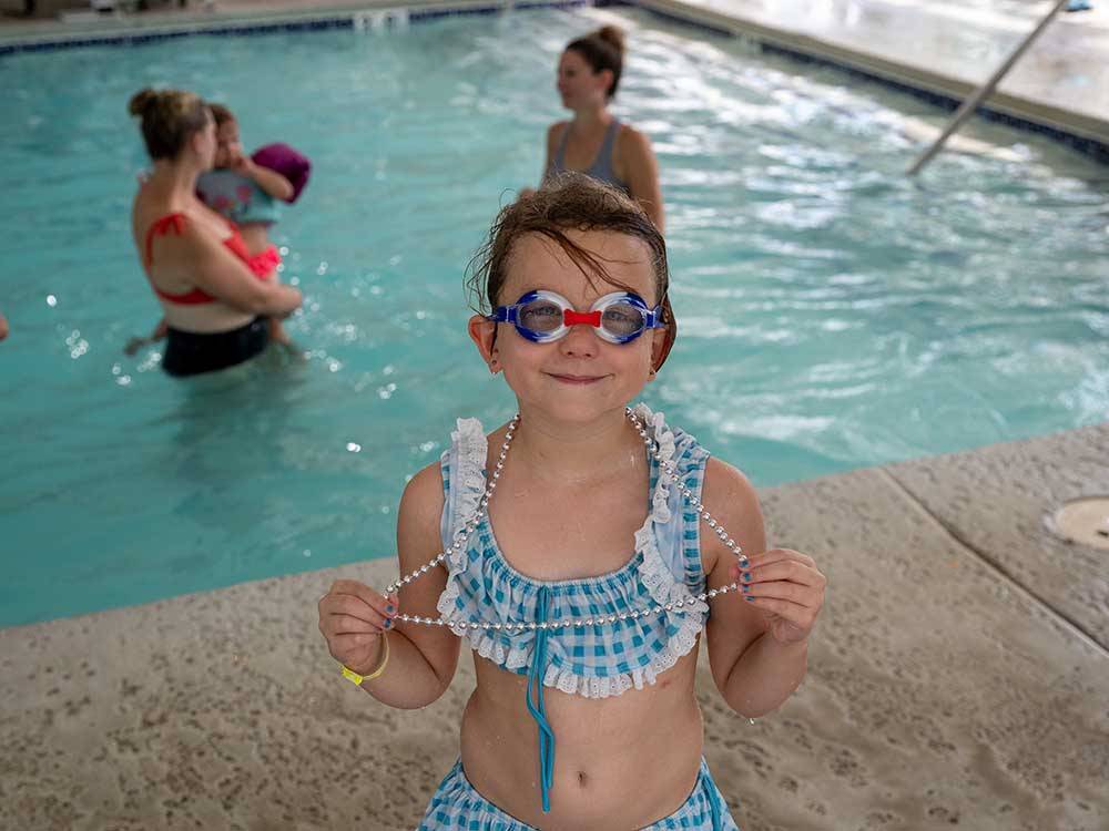 A girl with goggles on by the pool at FRANKENMUTH YOGI BEAR'S JELLYSTONE PARK CAMP-RESORT
