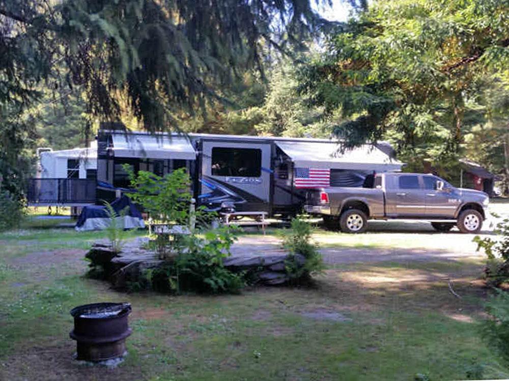 A trailer and truck parked in a shaded site at MYSTIC FOREST RV PARK