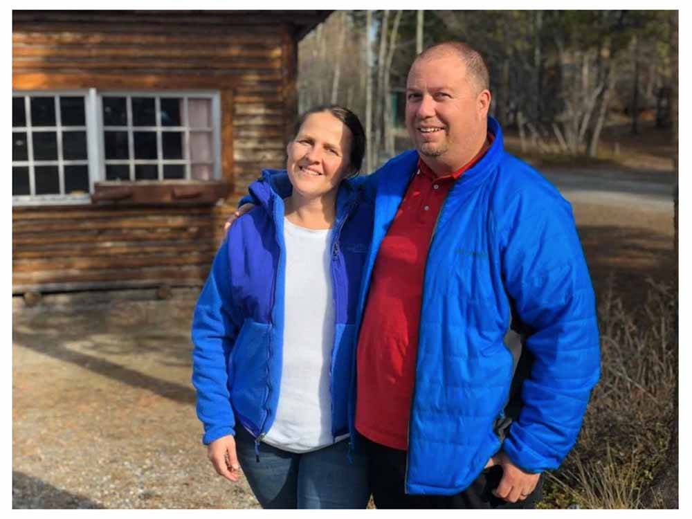 A smiling couple in blue jackets at CARIBOU RV PARK
