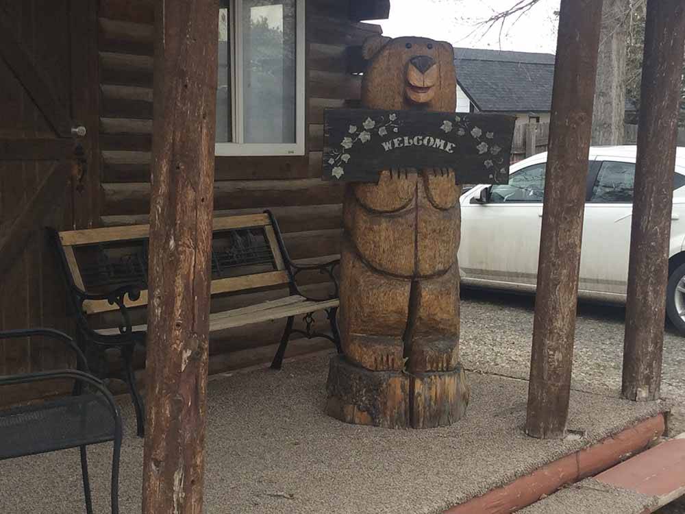 A wooden bear holding a welcome sign at AB CAMPING RV PARK