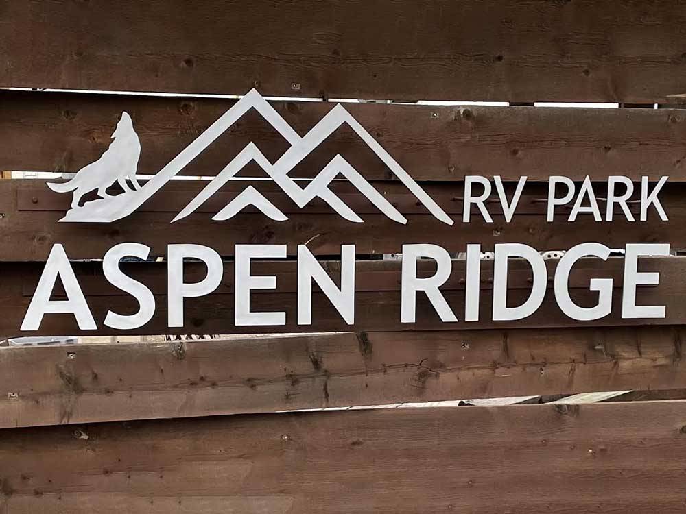 A wooden fence with the park name on it at ASPEN RIDGE RV PARK