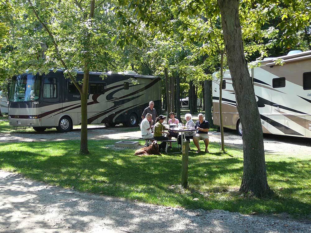 People sitting at picnic table, with motorhomes in the background at CAMPERS COVE CAMPGROUND