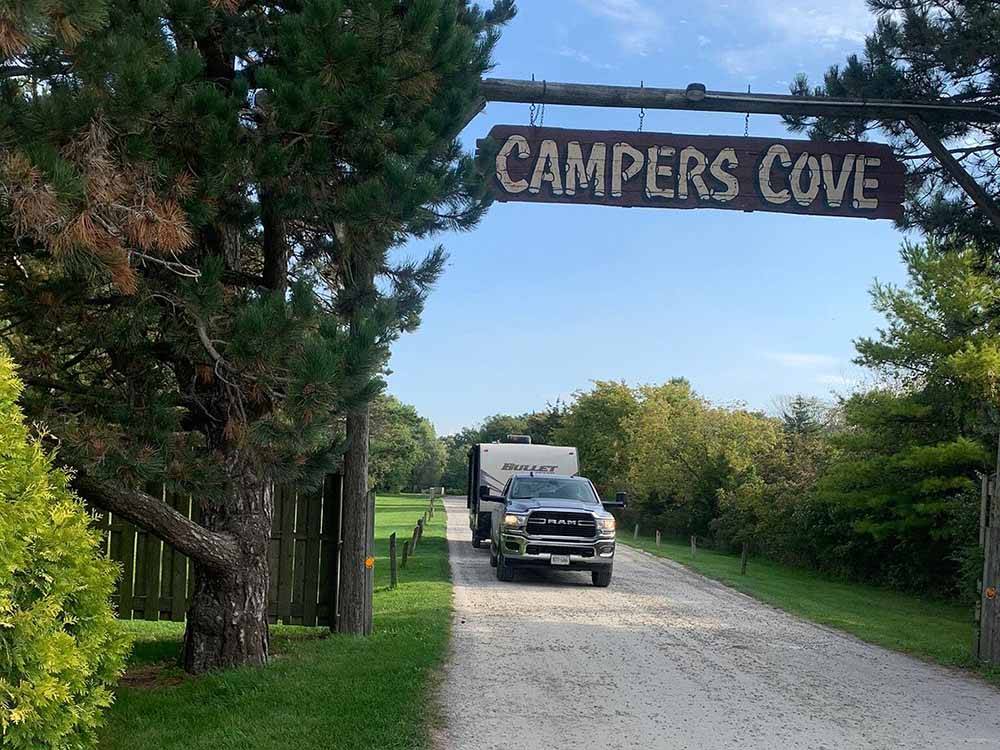 A truck and trailer driving under the front entrance sign at CAMPERS COVE CAMPGROUND
