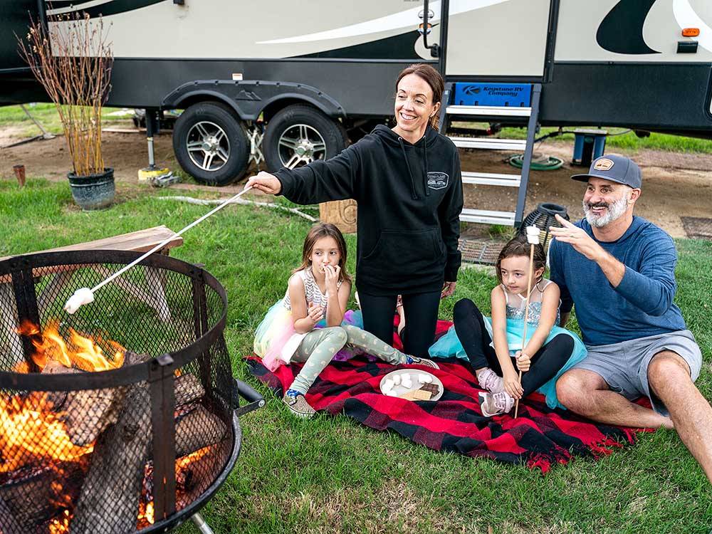 A family roasting marshallows at FLYING FLAGS RV RESORT & CAMPGROUND