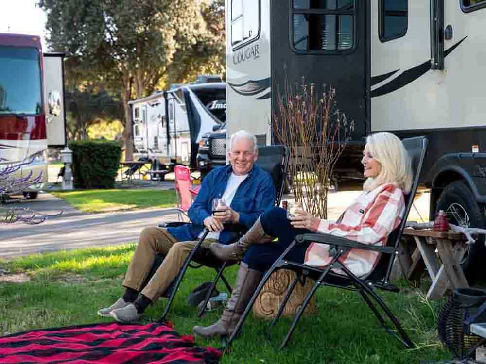 A couple of people sitting outside of a trailer at FLYING FLAGS RV RESORT & CAMPGROUND