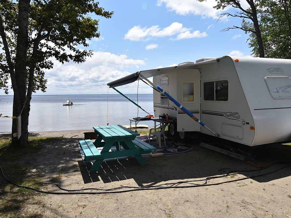 A travel trailer at an RV site next to the water at GLENROCK COTTAGES & TRAILER PARK