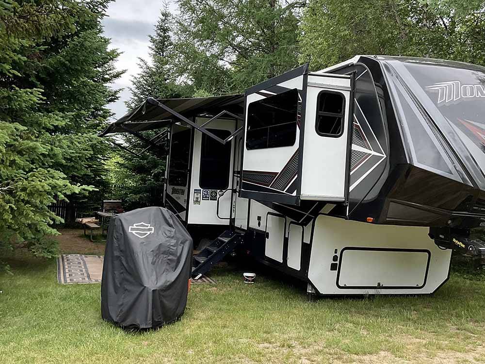 A fifth wheel trailer in a grassy RV site at BEECH HILL CAMPGROUND & CABINS