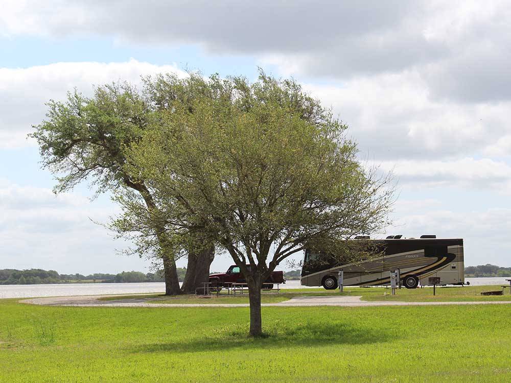 A motorhome and truck parked next to the lake at BRACKENRIDGE RECREATION COMPLEX - BRACKENRIDGE PARK & CAMPGROUND