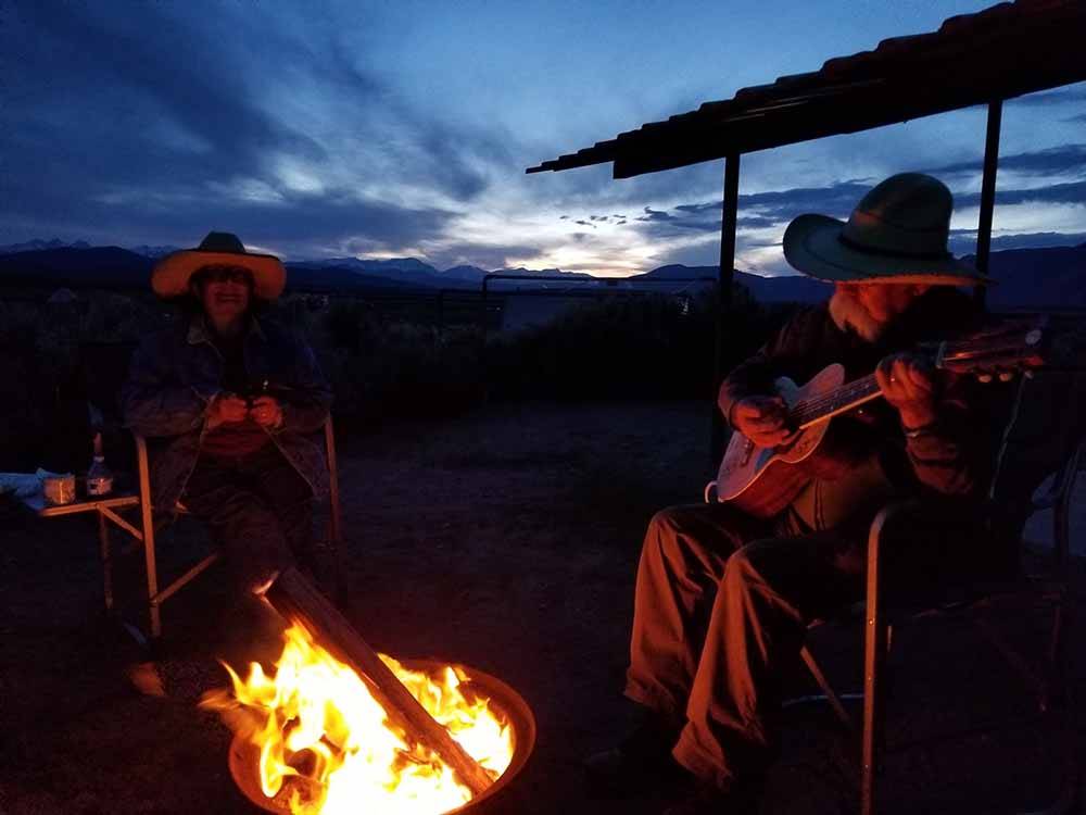A man playing a guitar at a fire pit at BROWN'S TOWN CAMPGROUND
