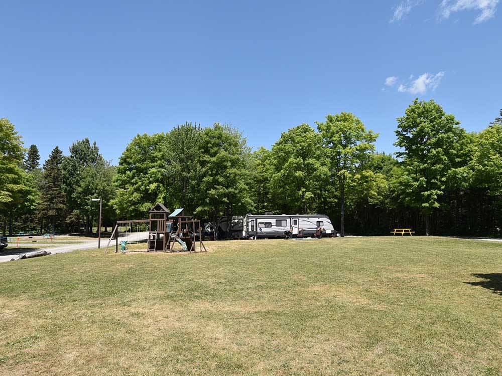 Playground, grassy area and travel trailer at GLENVIEW COTTAGES & RV PARK