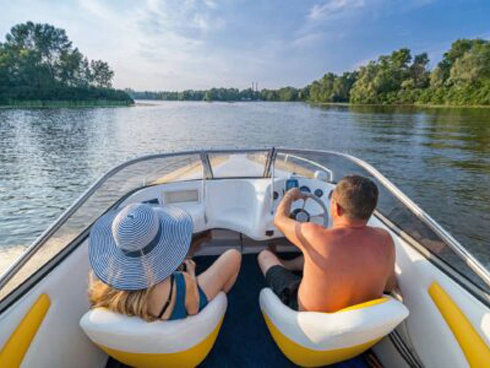 Two people driving a boat down the river at DELAWARE RIVER FAMILY CAMPGROUND