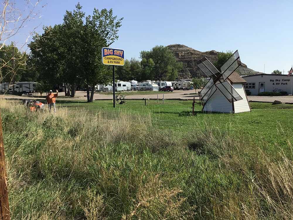 A windmill next to the park sign at BIG SKY CAMP & RV PARK