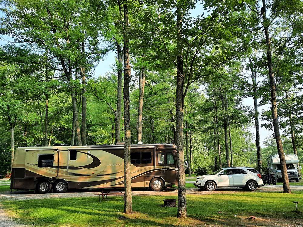 A motorhome and car in a pull thru site at HIDDEN HILL FAMILY CAMPGROUND