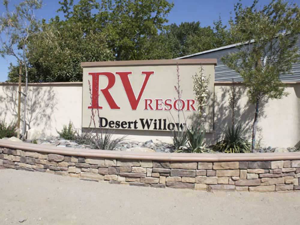 Campground front entrance sign with red font on desert themed brick wall at DESERT WILLOW RV RESORT