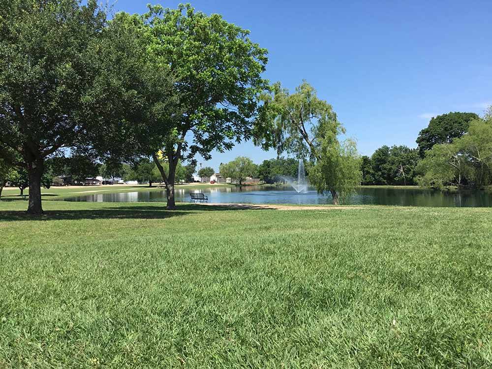A grassy area in front of the lake at HOUSTON WEST RV PARK