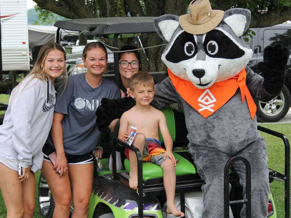 Kids on a golf cart with the raccoon mascot at BEYONDER GETAWAY AT WHEELER LAKE