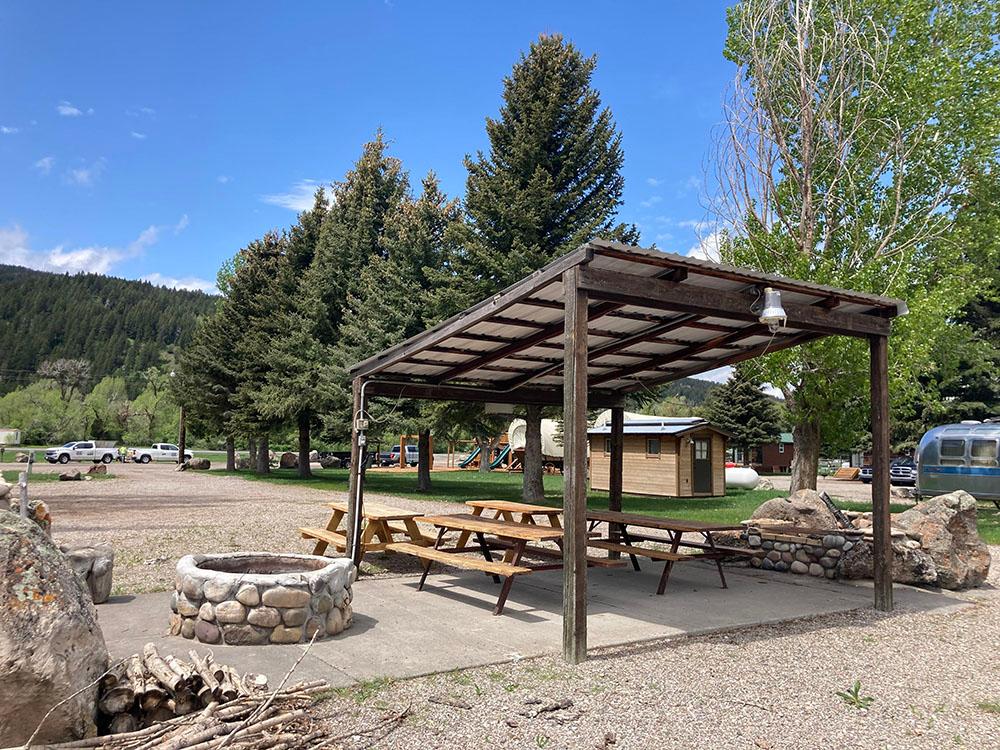 Picnic benches under a pavilion with a fire pit at SWAN VALLEY RV PARK