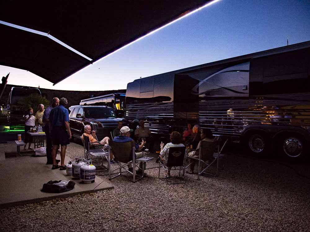 People hanging out around a motorhome at dusk at MCARTHUR'S TEMPLE VIEW RV RESORT