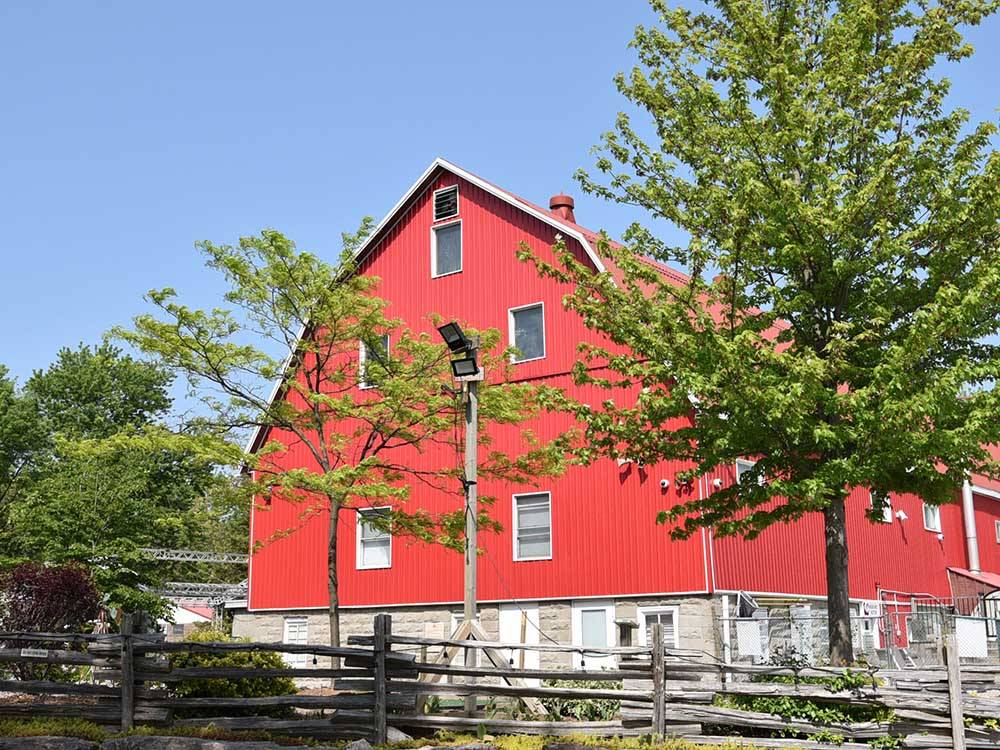 A big red barn by trees at CAMPARK RESORTS FAMILY CAMPING & RV RESORT