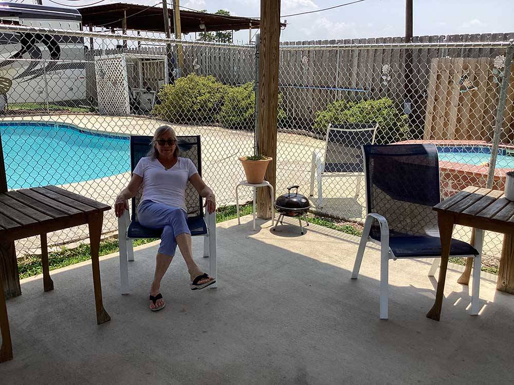A lady in a sitting area next to the pool at JUDE TRAVEL PARK OF NEW ORLEANS