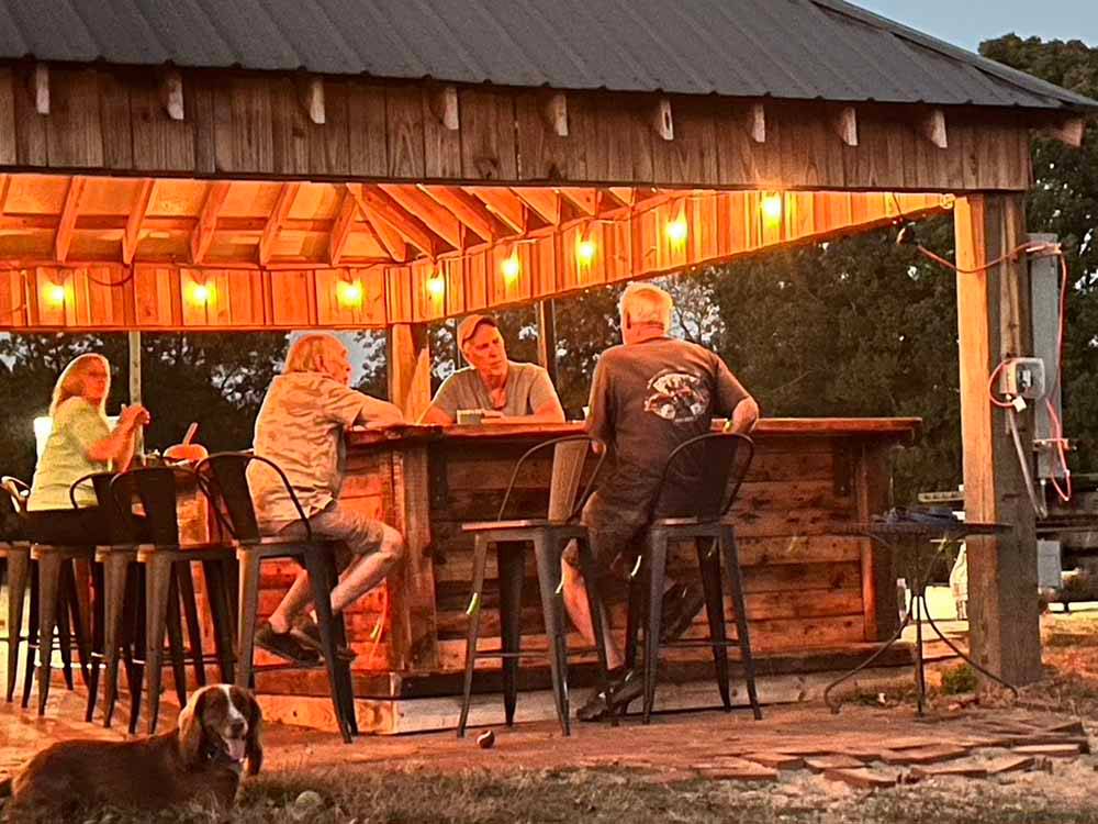 A group of people sitting under the pavilion at Van Hoy Farms Family Campground