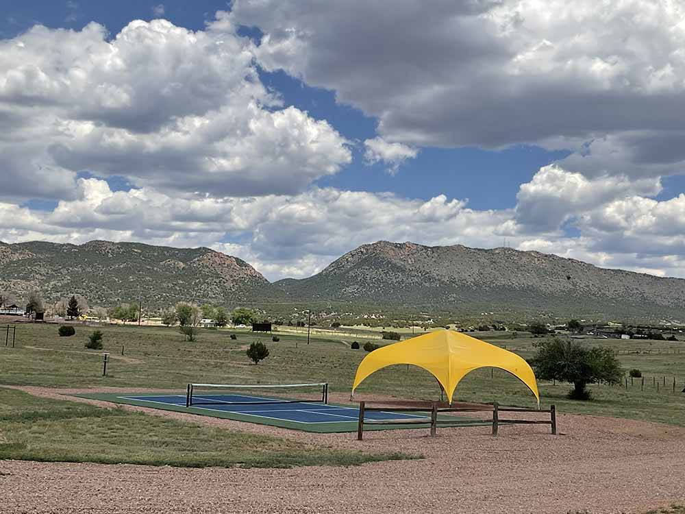 Yellow canopy and pickeball court in sprawling green landscape at ROYAL VIEW RV PARK