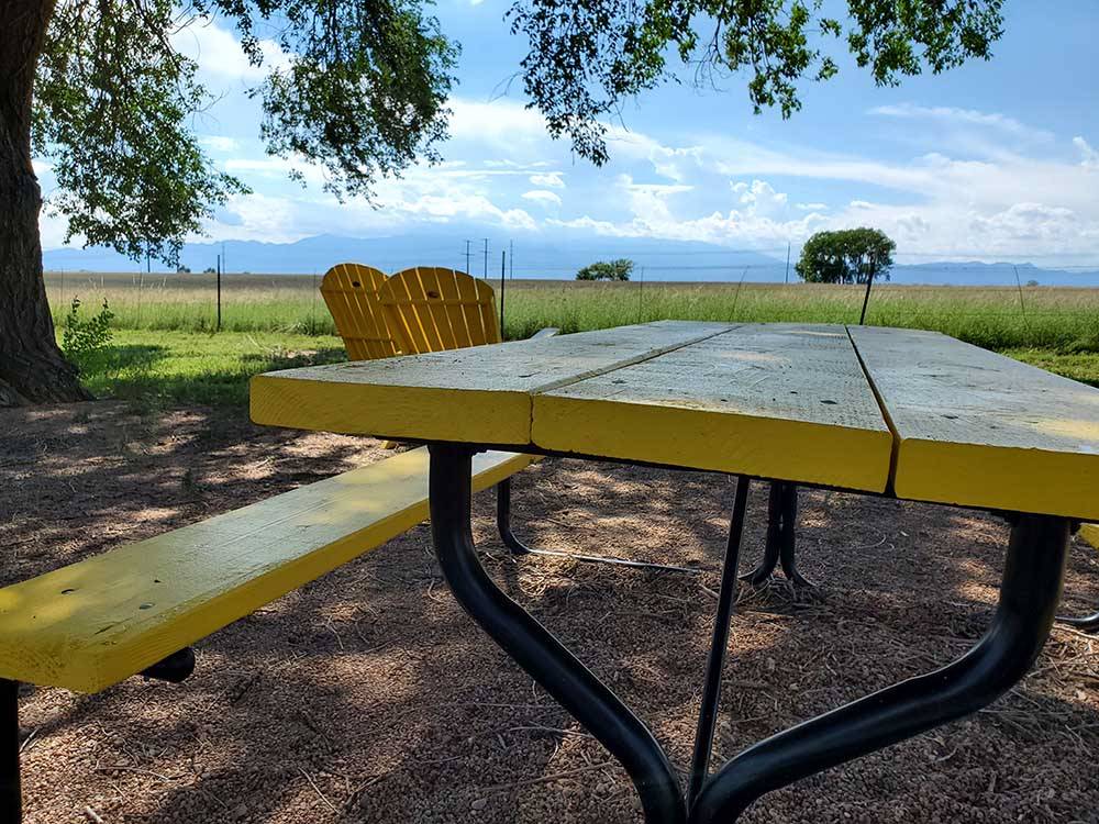 A yellow picnic bench and chairs at FALCON MEADOW RV CAMPGROUND