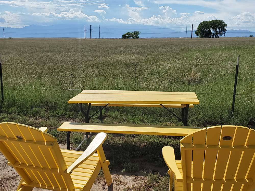 Two yellow chairs overlooking a field at FALCON MEADOW RV CAMPGROUND