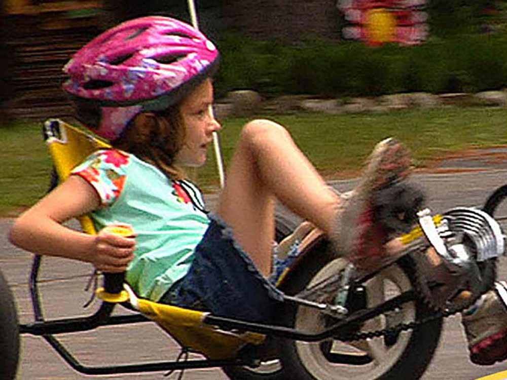 A girl with a pink helmet riding a bike at LEDGEVIEW RV PARK