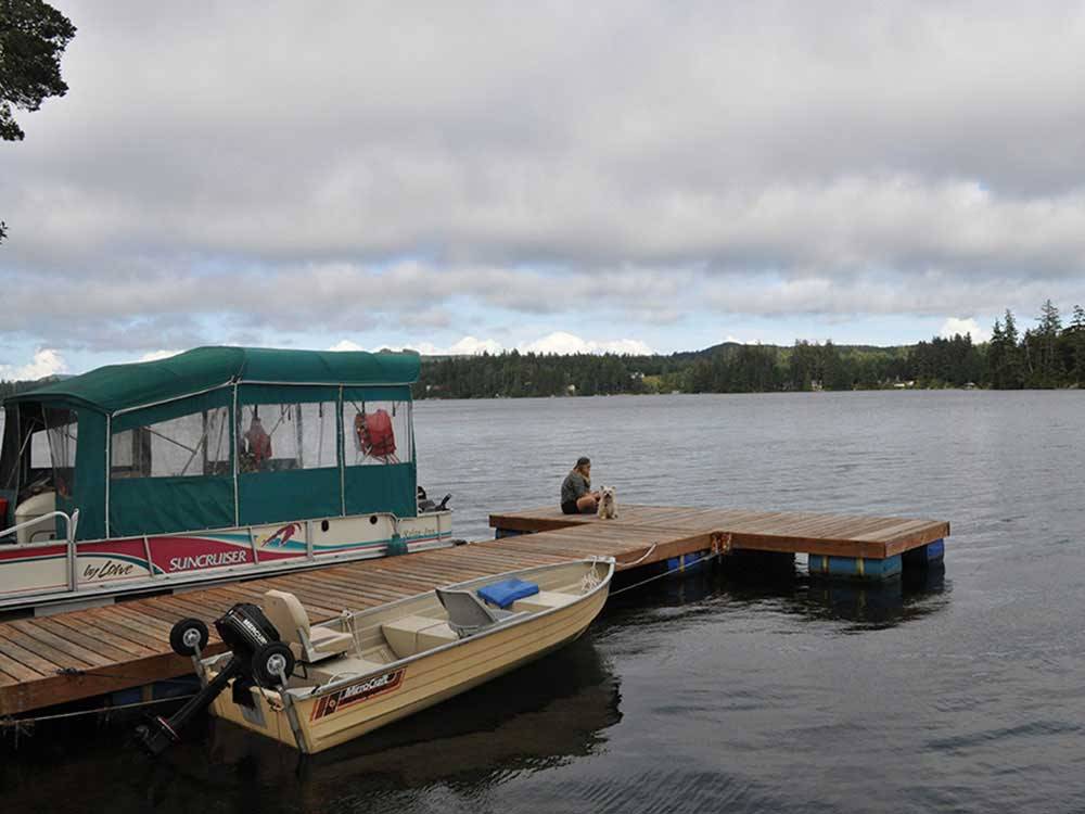 A person sitting on a dock with boats at WOAHINK LAKE RV RESORT