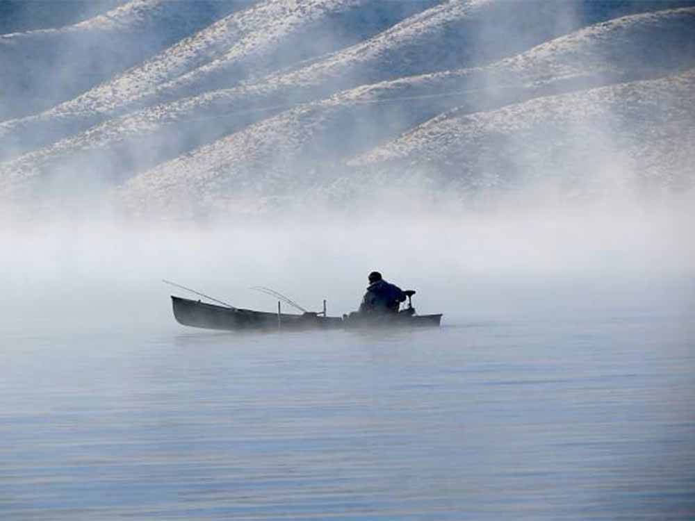 A fisherman on a boat on a foggy lake at TOPAZ LODGE RV PARK & CASINO