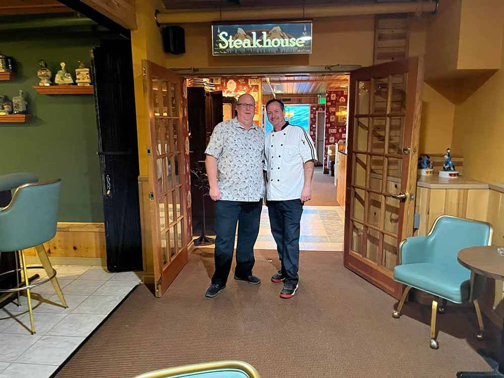 A couple of men standing in front of the steakhouse doorway at TOPAZ LODGE RV PARK & CASINO